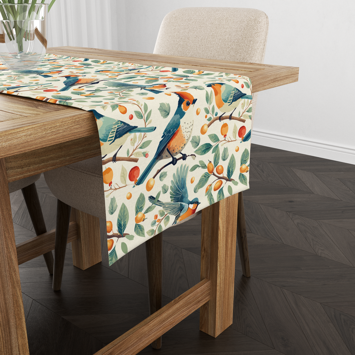 Cream table runner with blue and orange birds among branches with berries and citrus fruit, shown from another angle on a wooden table with tableware