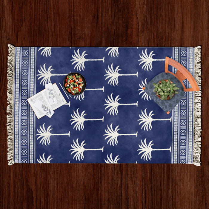 Top-down flat lay of the palm tree silhouette Dhurrie rug styled with a salad bowl, notecards, and a potted plant