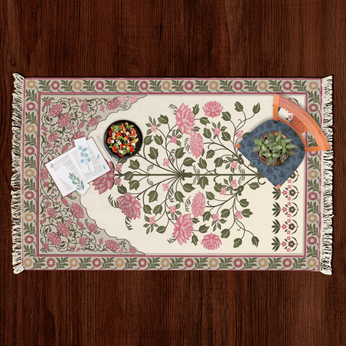 Top-down flat lay of the rose bouquet floral medallion Dhurrie rug styled with a salad bowl, notecards, and a potted plant