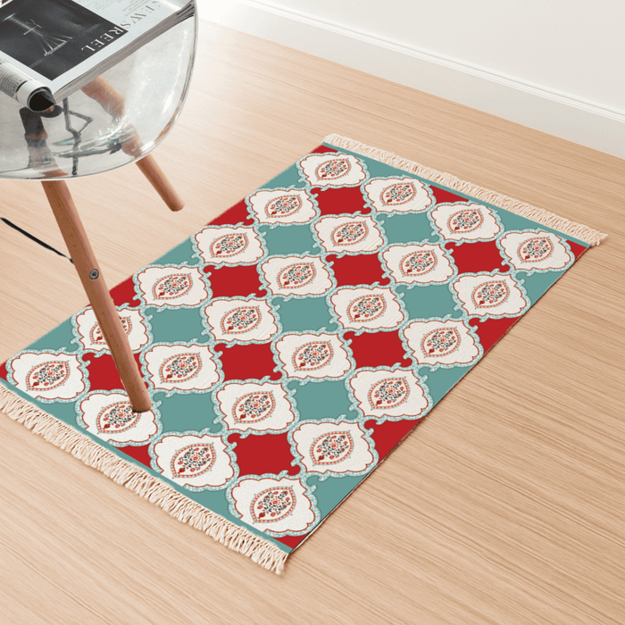 Angled view of the checkerboard floral medallion Dhurrie rug on a light wood floor beside a chair