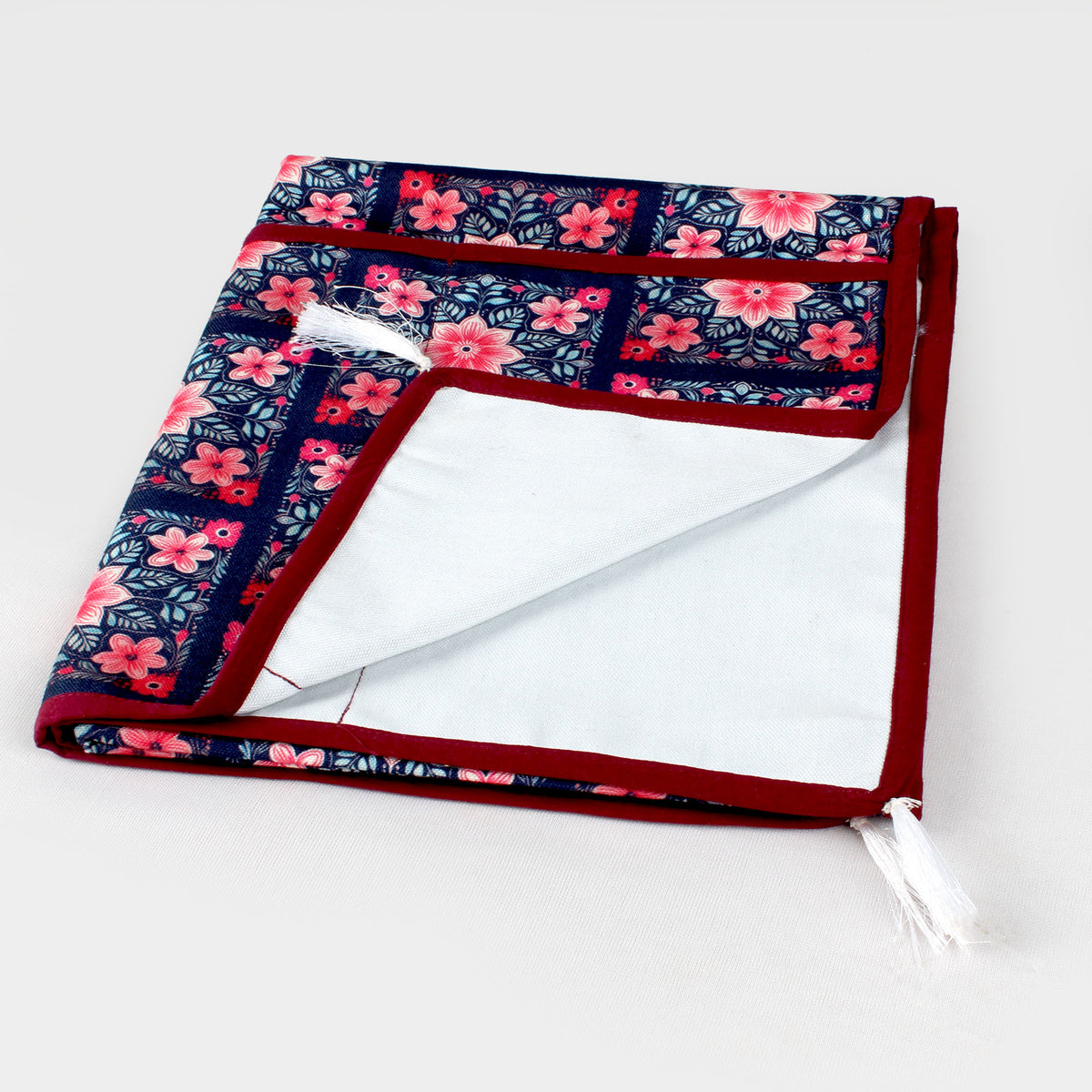 Folded floral tile print fridge cover showing the white storage pocket and a white tassel