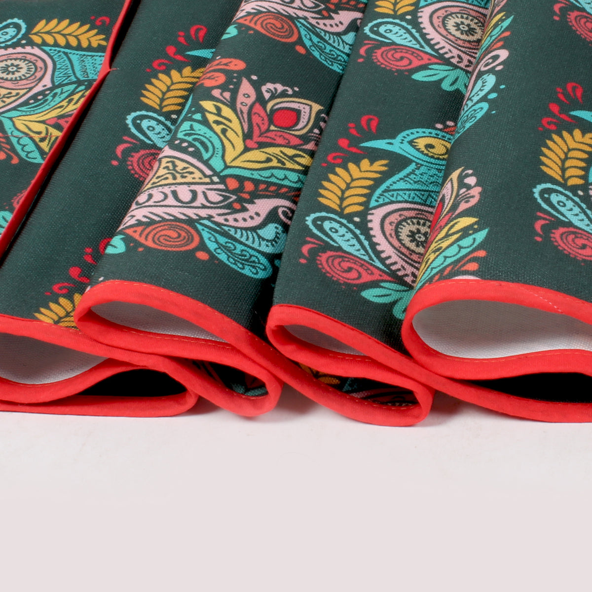 Close-up of folded fridge cover edges showing red trim and the peacock-paisley print fabric