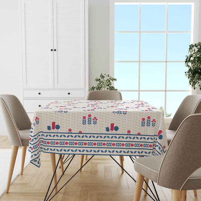 Cream tablecloth with a minimal navy leaf motif and red-berry accents, striped border, shown top-down on a dining table
