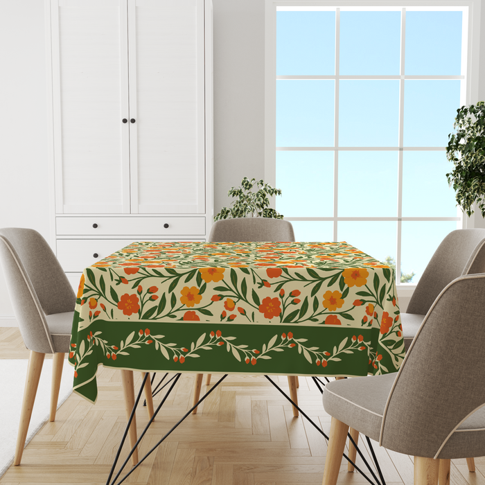 Cream tablecloth with a bright orange-and-yellow floral print, deep olive-green vine border, set on a 6 seater dining table with matching chairs