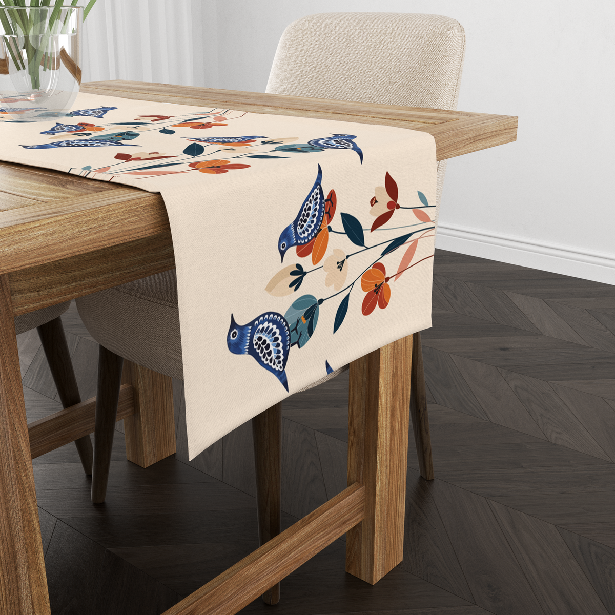 Cream table runner with navy folk-art birds and rust-orange florals, shown from another angle on a wooden table with tableware