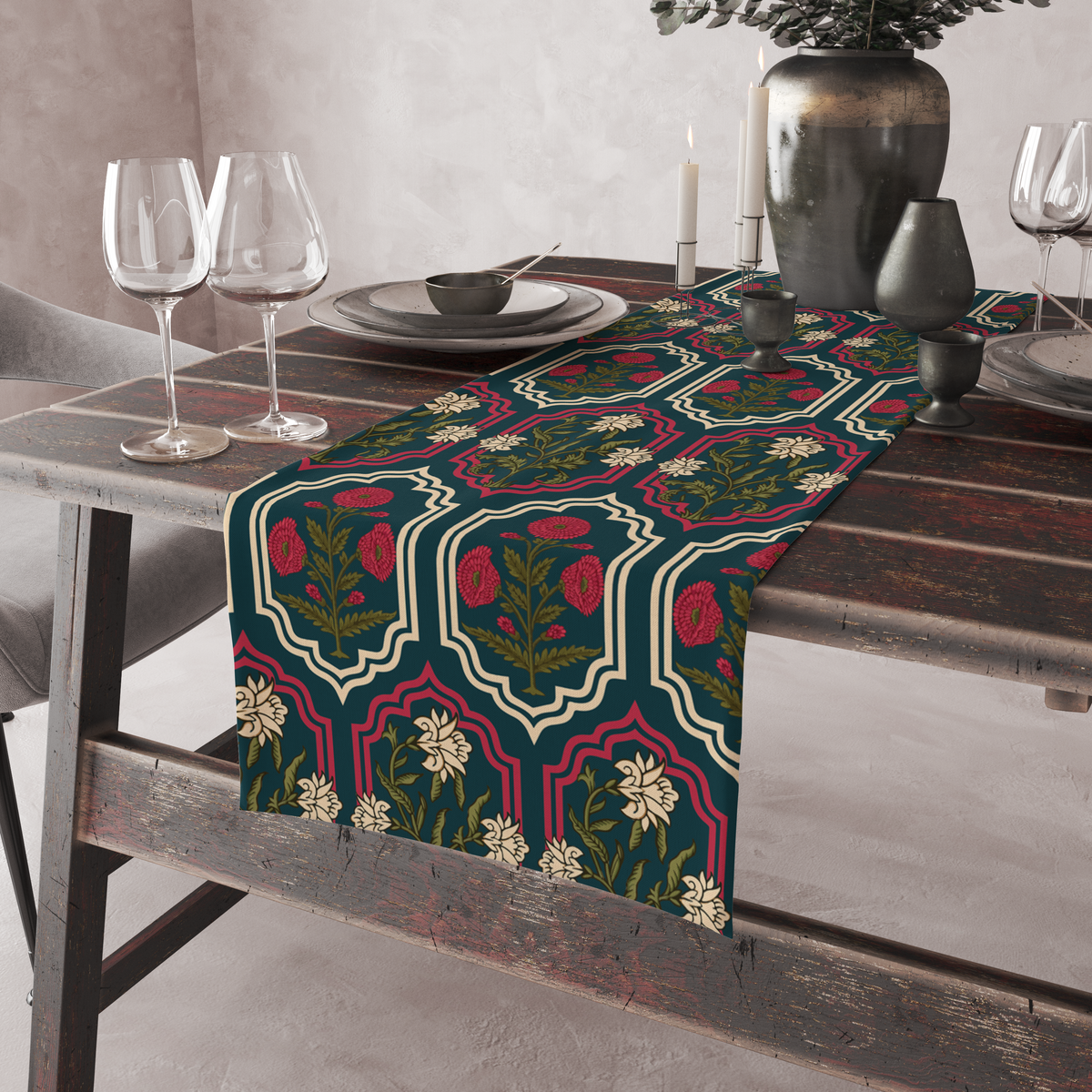 Deep teal table runner with ornate red and cream medallion frames and floral motifs, shown on a rustic table with wine glasses