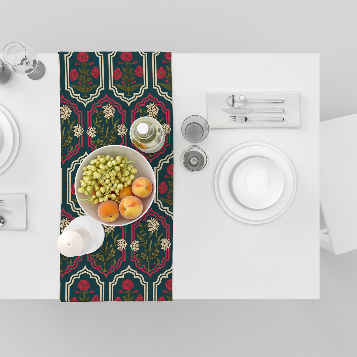 Deep teal table runner with ornate red and cream medallion frames and floral motifs, shown top-down with fruit bowl and tableware