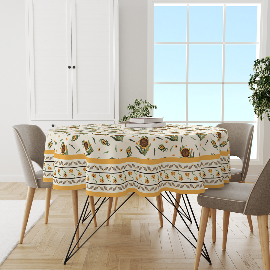 Cream round tablecloth with sunflower print and mustard yellow floral border, on a round table