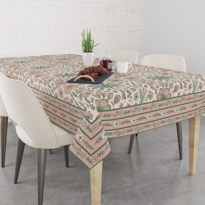 Blush-pink tablecloth with sage-green floral and palm-leaf motifs, matching striped border, set on a 6 seater dining table with matching chairs
