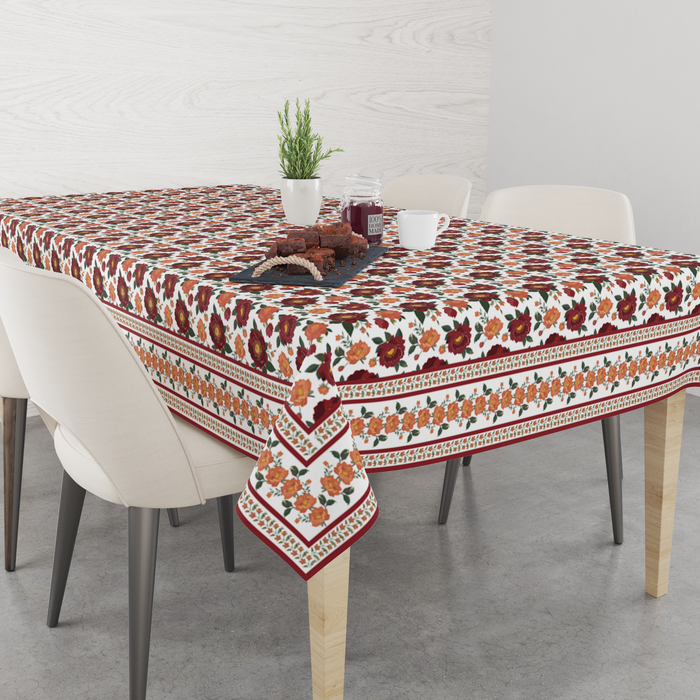 Cream tablecloth with clustered maroon rose bunches, orange floral border, set on a 6 seater dining table with matching chairs