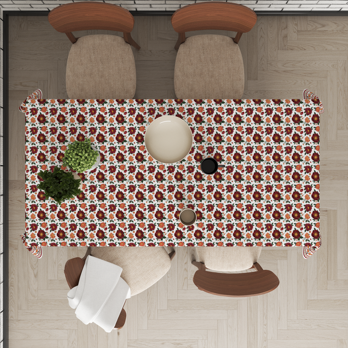 Cream tablecloth with clustered maroon rose bunches, orange floral border, styled with tableware for a dining setting