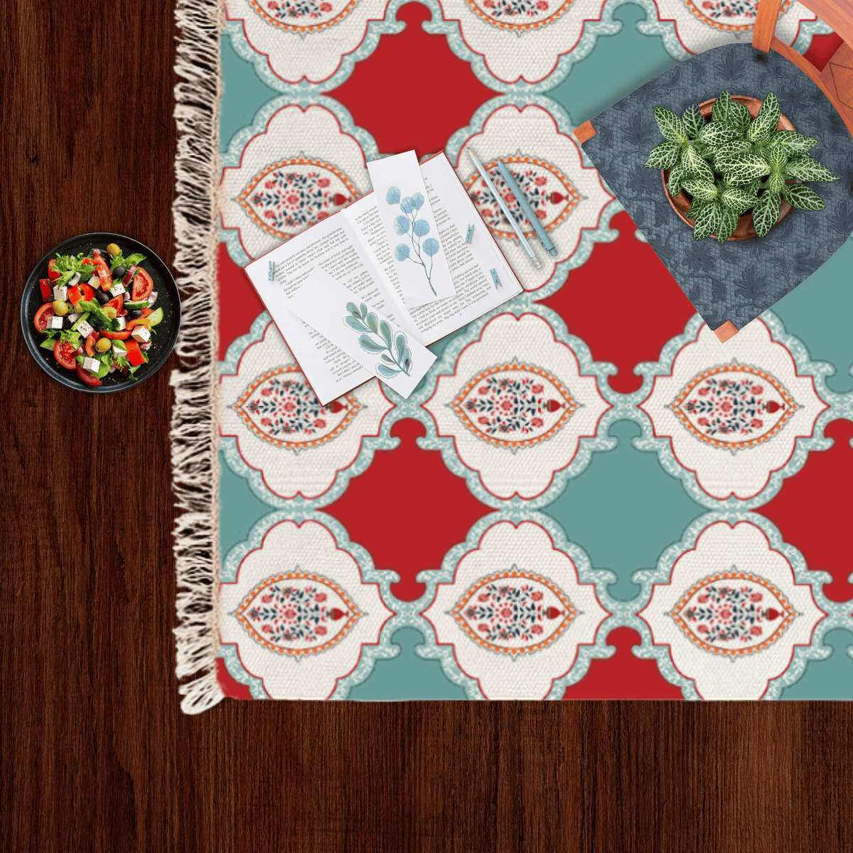 Close-up corner of the checkerboard floral medallion Dhurrie rug styled with a small salad bowl and a potted plant