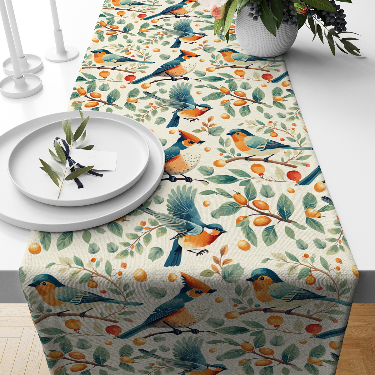 Cream table runner with blue and orange birds among branches with berries and citrus fruit, styled on a wooden dining table