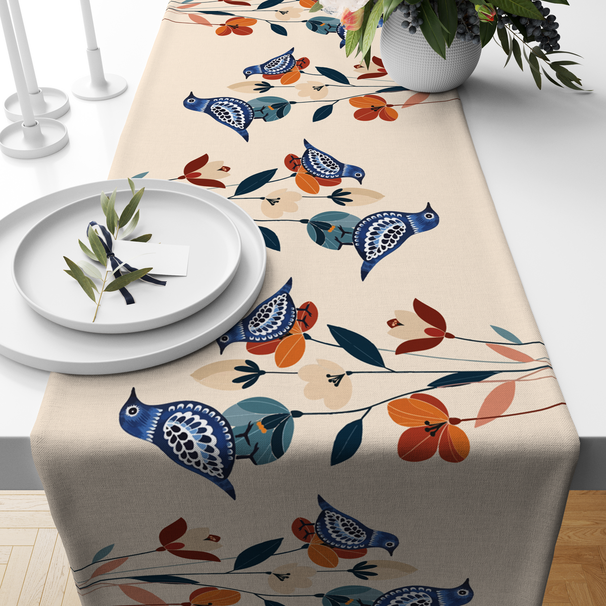Cream table runner with navy folk-art birds and rust-orange florals, styled on a wooden dining table