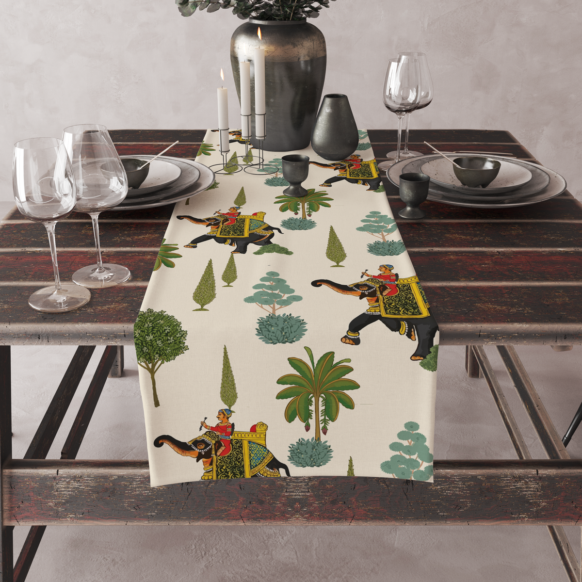 Cream table runner with decorated royal elephants, riders, and tree motifs, set on a full dining table with candles