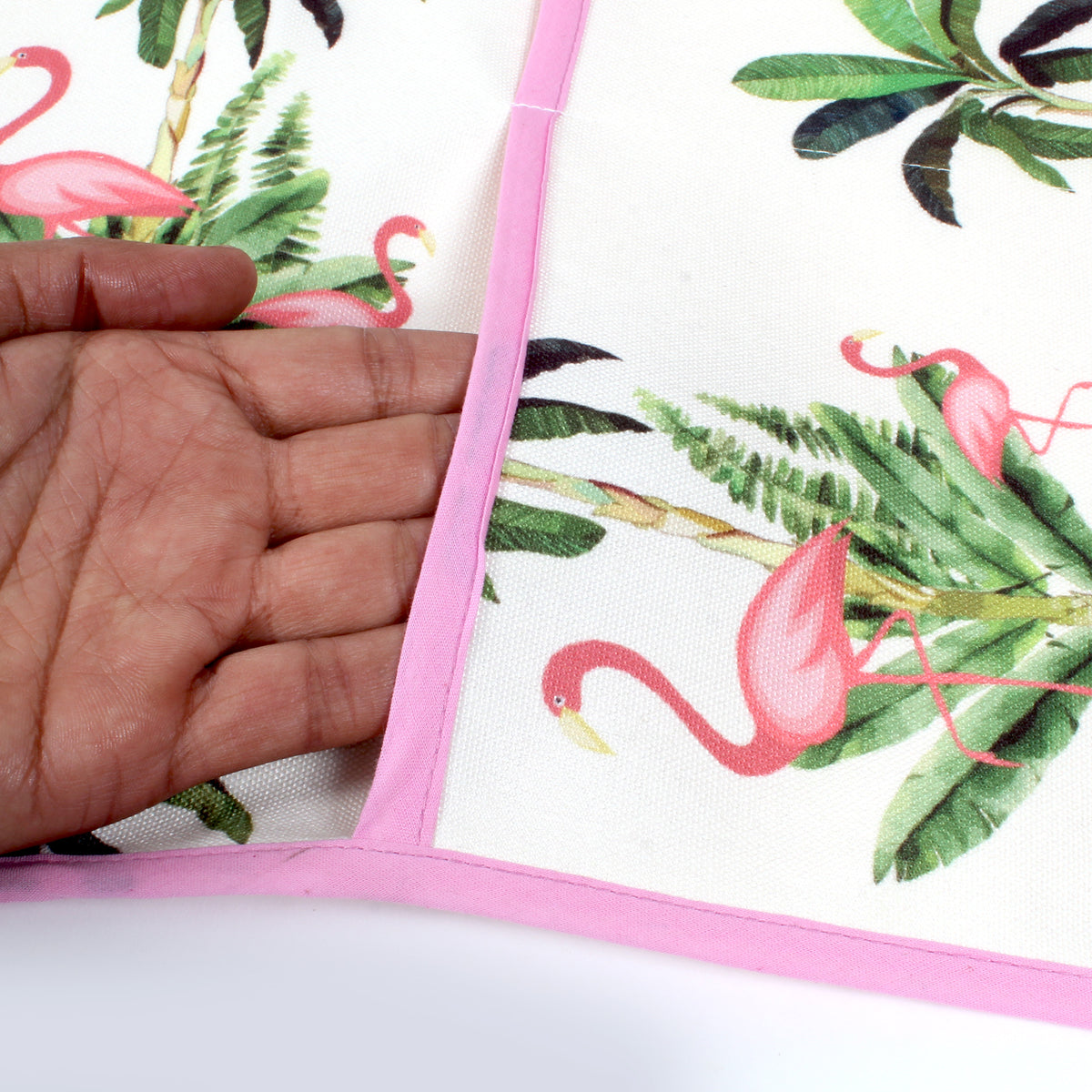 Close-up of a hand feeling the soft cotton fabric of the flamingo print fridge cover