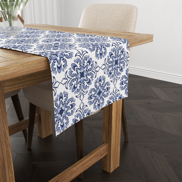 White table runner with a Turkish-tile-inspired indigo medallion print, shown from another angle on a wooden table with tableware