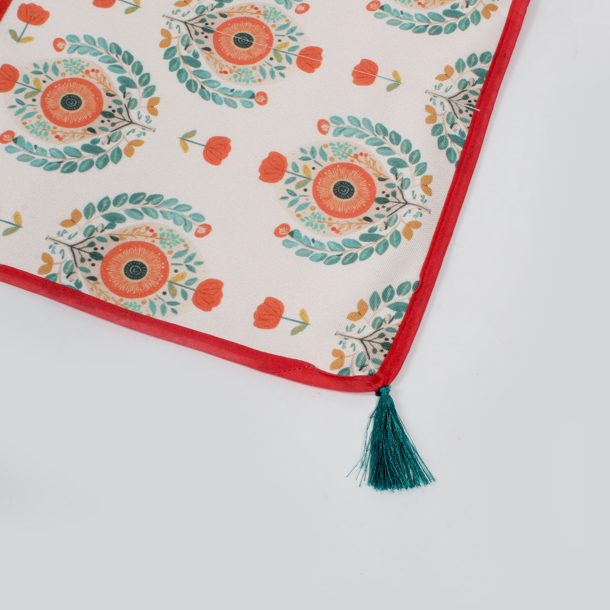 Close-up of the fridge cover's corner showing red piping and a teal tassel