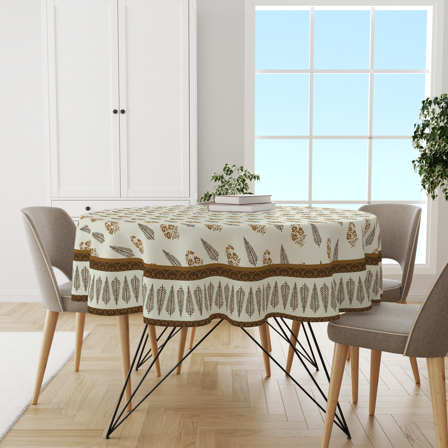 Cream round tablecloth with brown block-print feather and leaf border, on a dining table