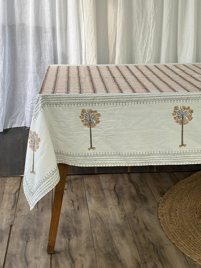 Cream tablecloth with a mustard tree-of-life motif border, styled with a full table setting