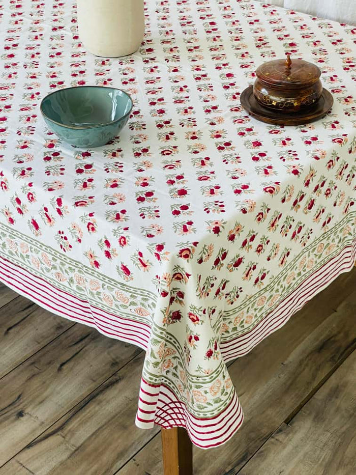 Cream tablecloth with a small red and pink ditsy floral print, striped and floral border, styled with a full table setting