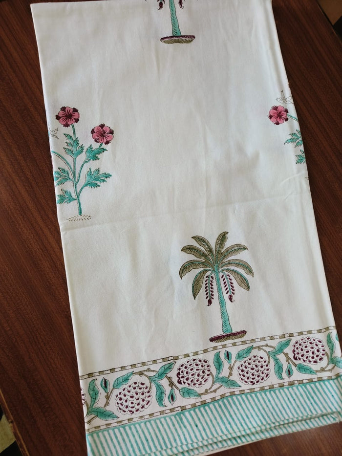 Cream tablecloth with palm-tree motifs and a pink floral border, styled with a full table setting