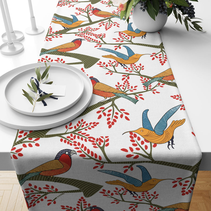 White cotton table runner with red and blue bird of paradise print, styled on a dining table
