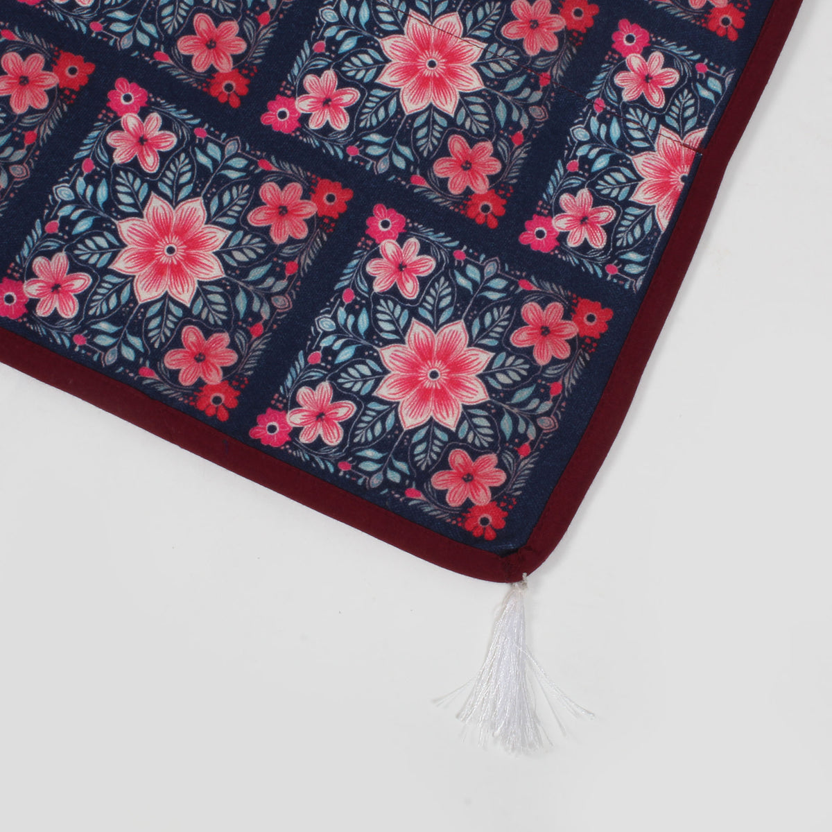 Close-up of the fridge cover's corner showing maroon trim and a white tassel